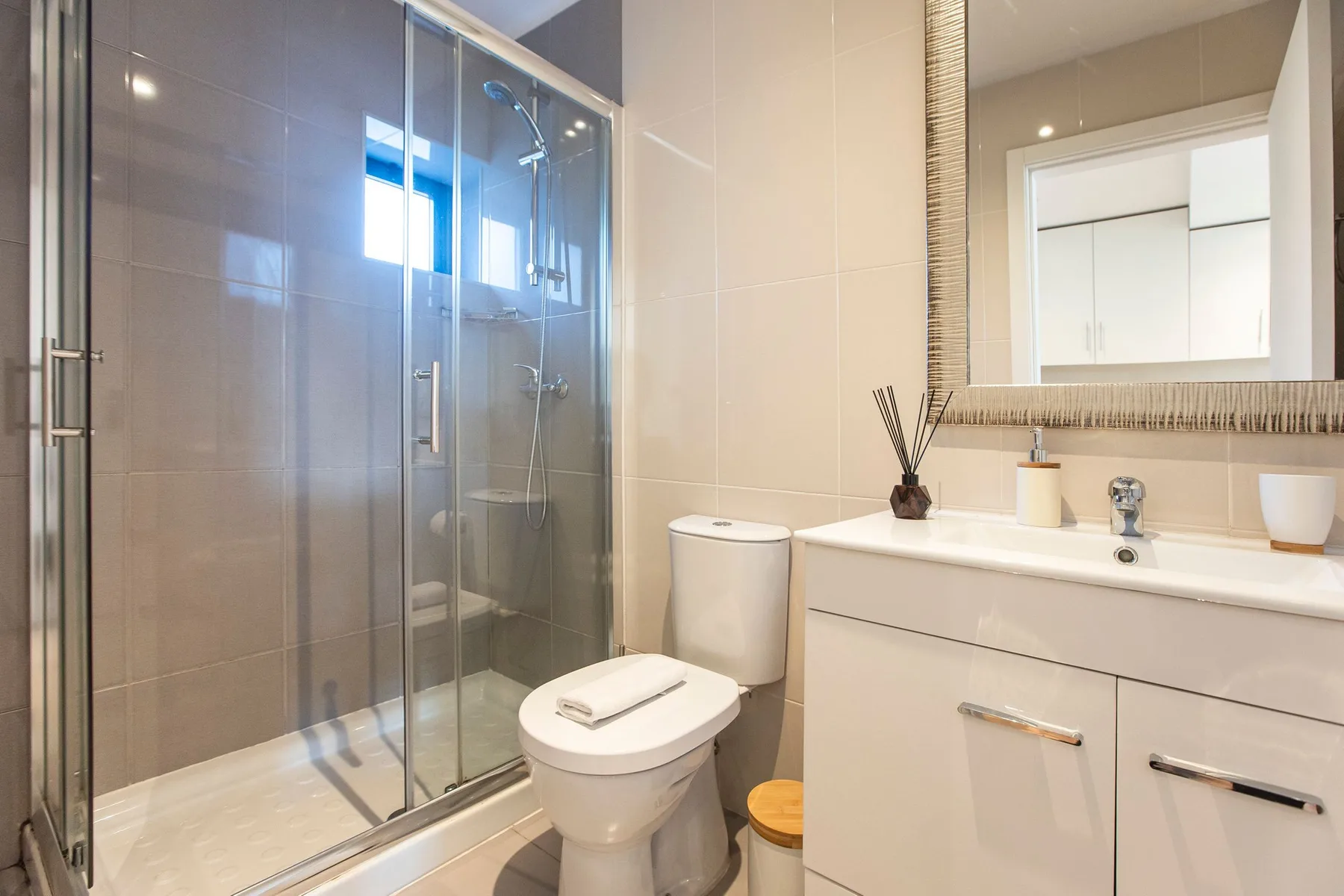 A bathroom with a glass shower, toilet, and sink vanity.