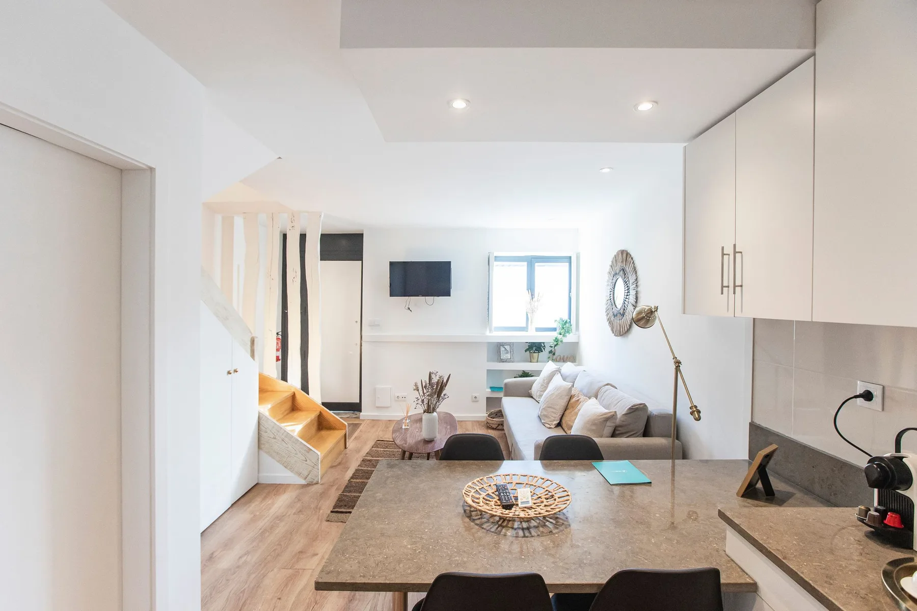 A bright living room with a dining table and a staircase.