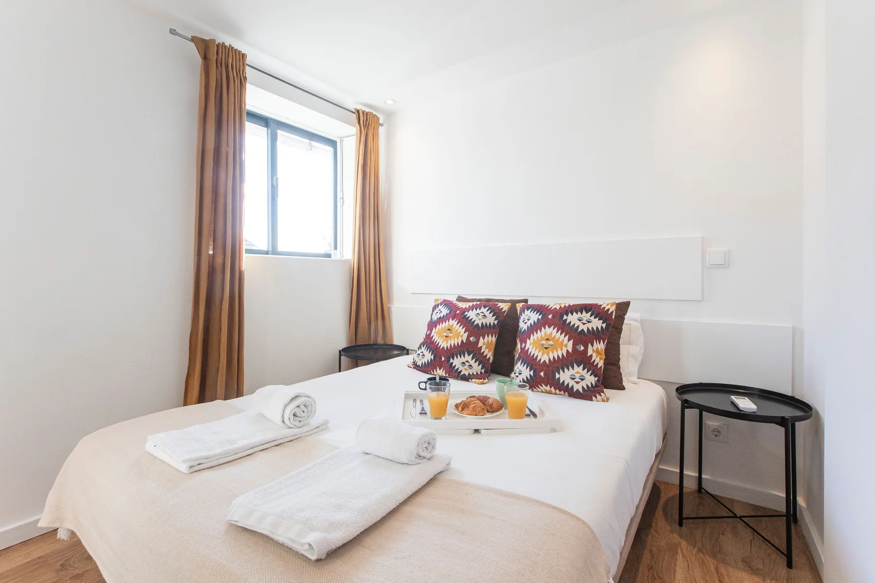 A bedroom with a bed, patterned pillows, and a window with curtains.