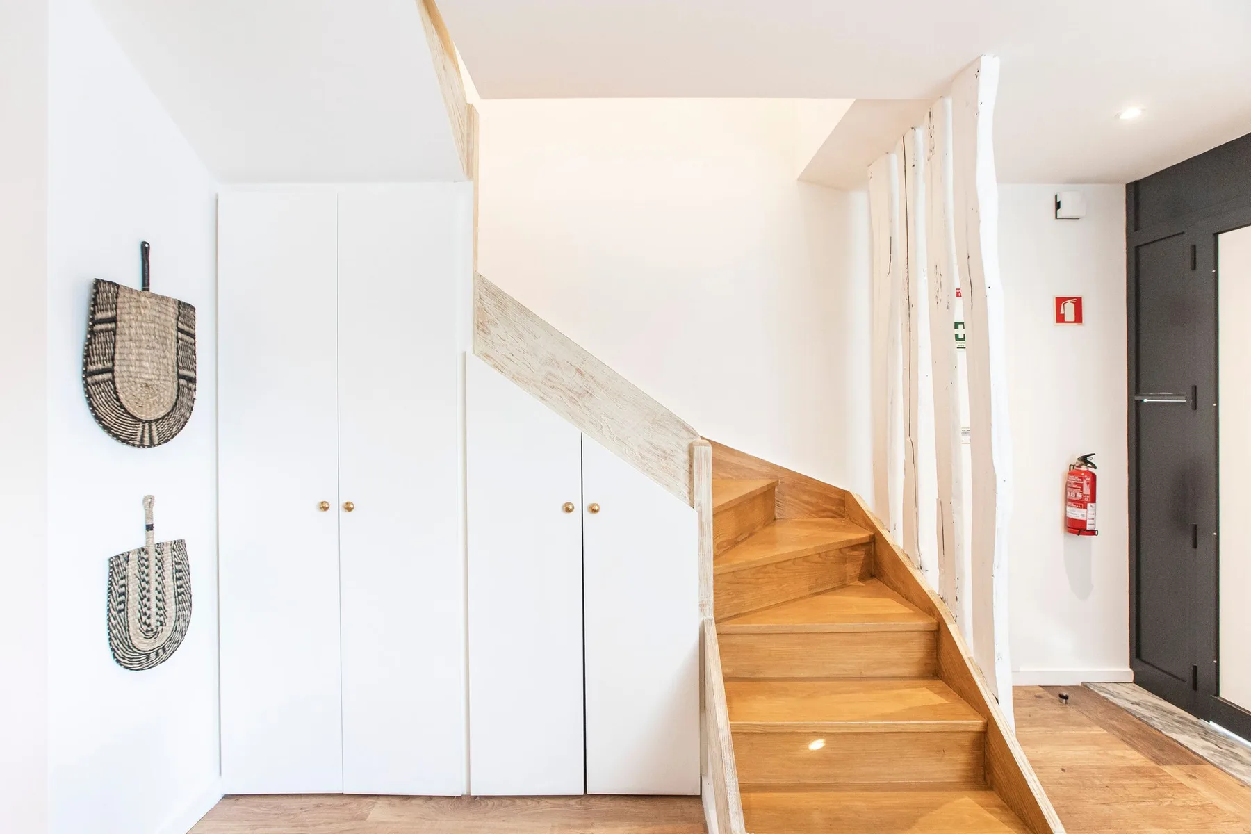 A bright entry hall with a wooden staircase and built-in storage.
