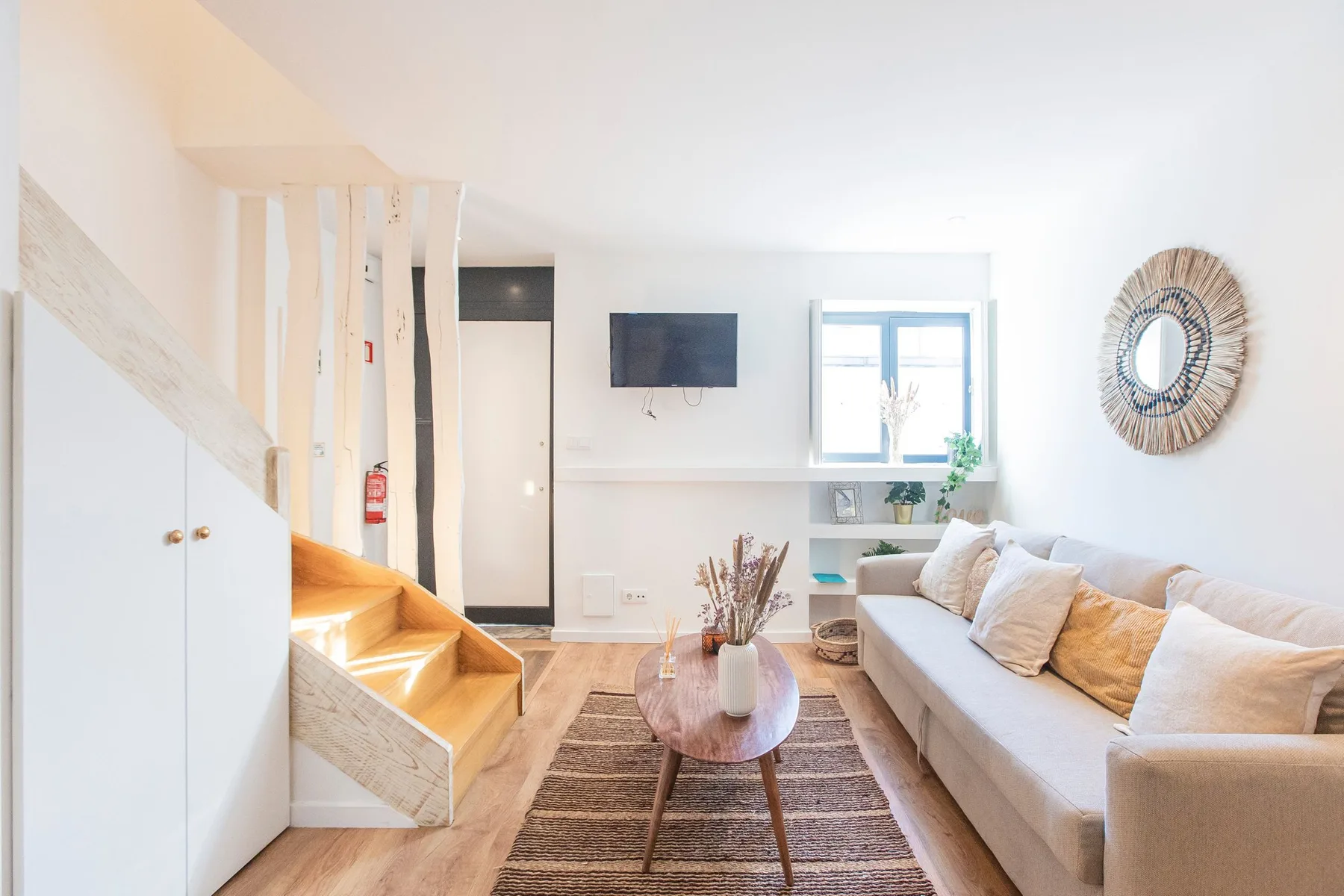 Bright living room with a sofa, coffee table, and staircase.