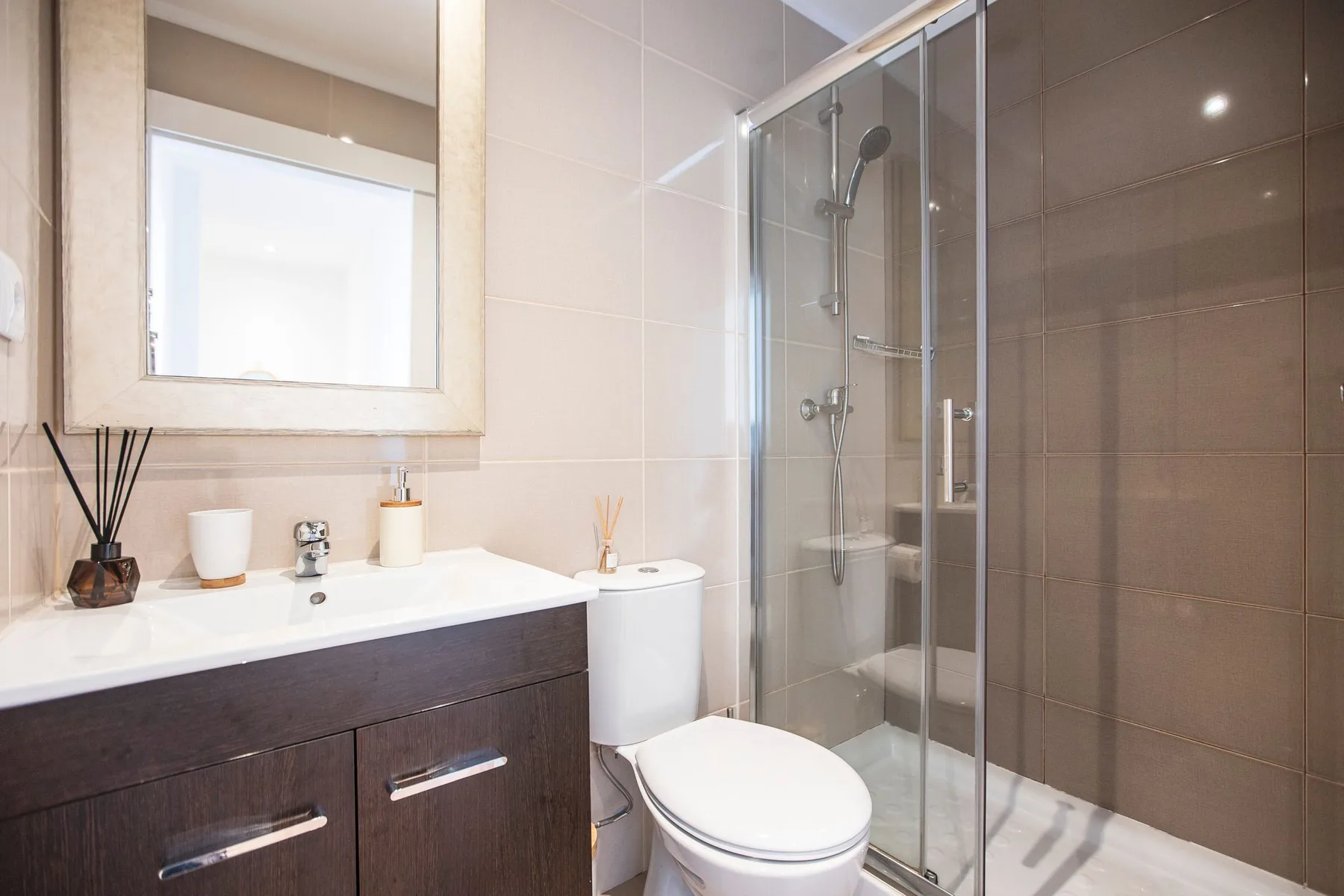 A bathroom with a vanity, mirror, toilet, and glass shower.