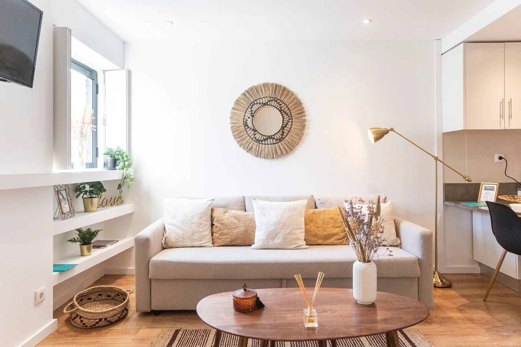 A bright living room with a sofa, round coffee table, and wall mirror.