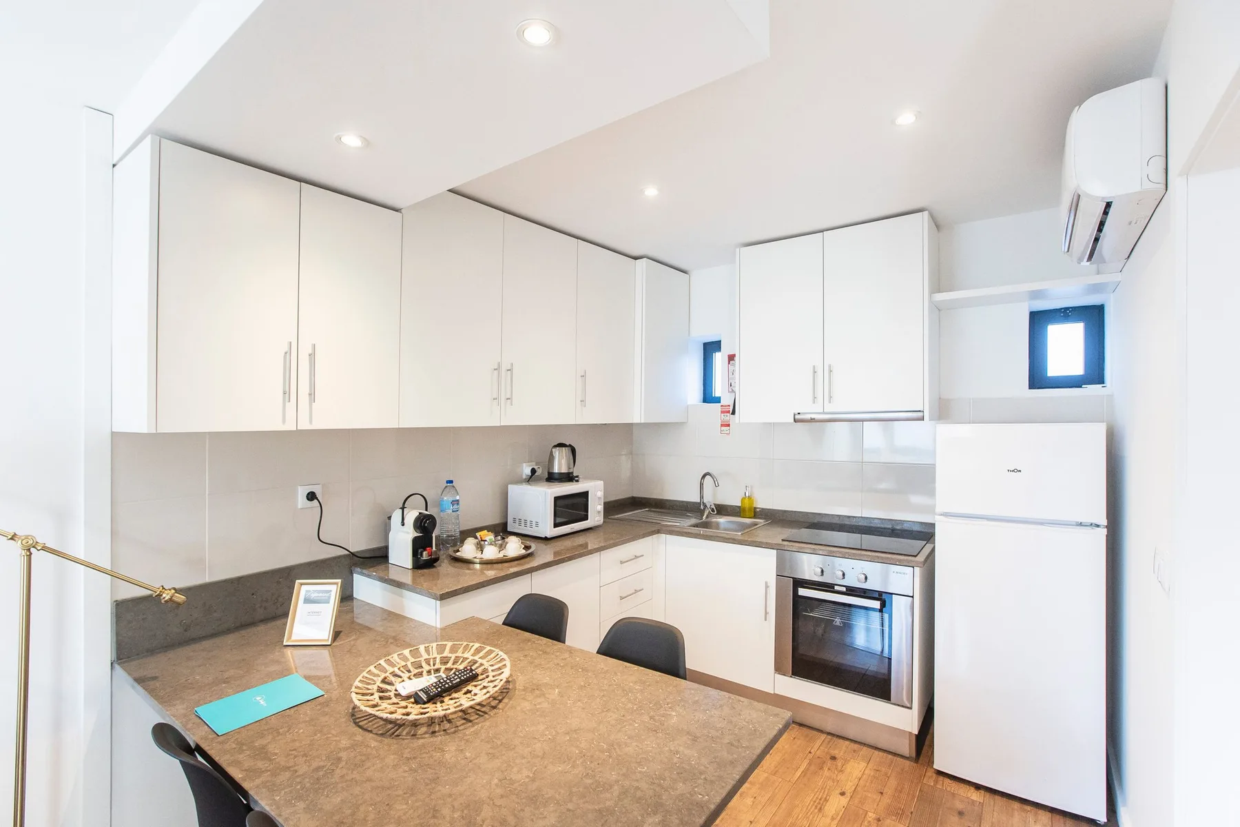 A bright kitchen with white cabinets, a dining table, and a built-in oven.