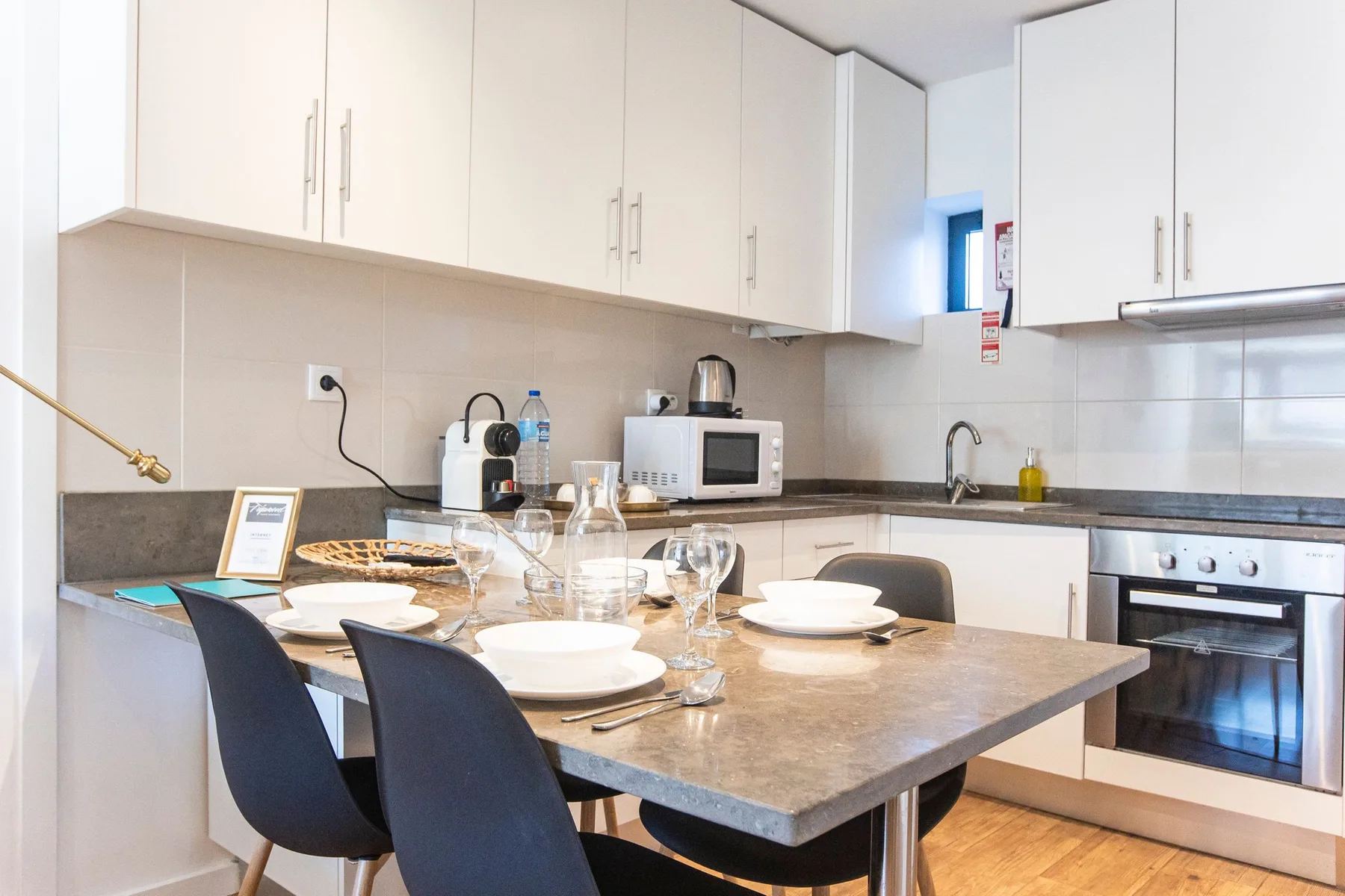 A bright kitchen with a dining table set with plates and glassware.