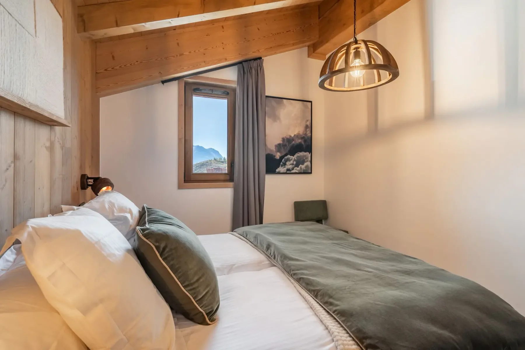 Cozy bedroom with wooden walls, a double bed with green accents, a window, modern lamp, and artwork on the wall.