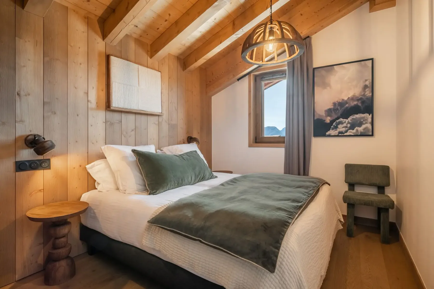 Cozy bedroom with wooden walls, a double bed with green accents, a window, modern lamp, and artwork on the wall.