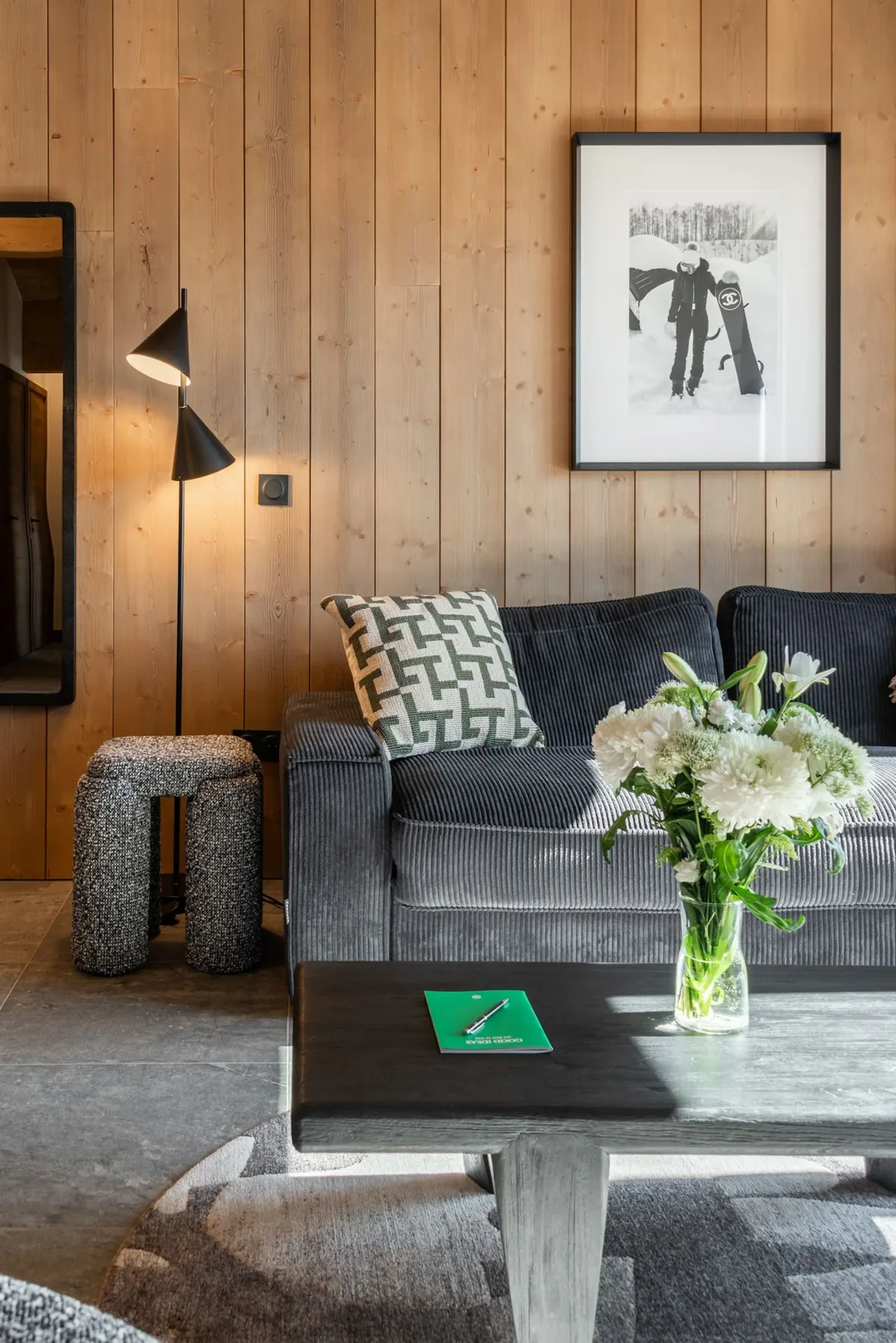 A cozy living room with wooden beams, modern furniture, a dining table, and large windows offering a mountain view.