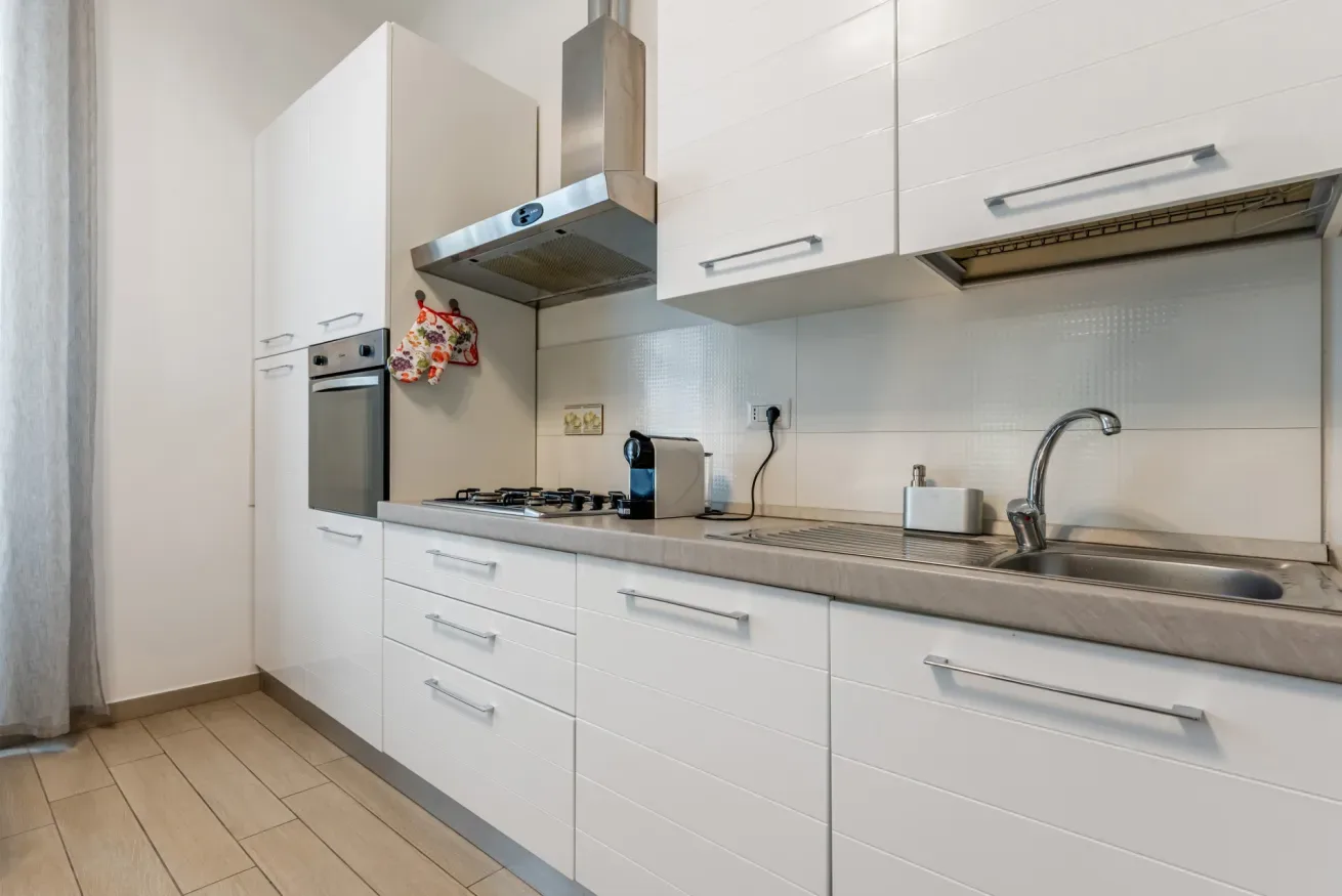 Una cocina moderna con gabinetes blancos, una placa de cocina y un fregadero.