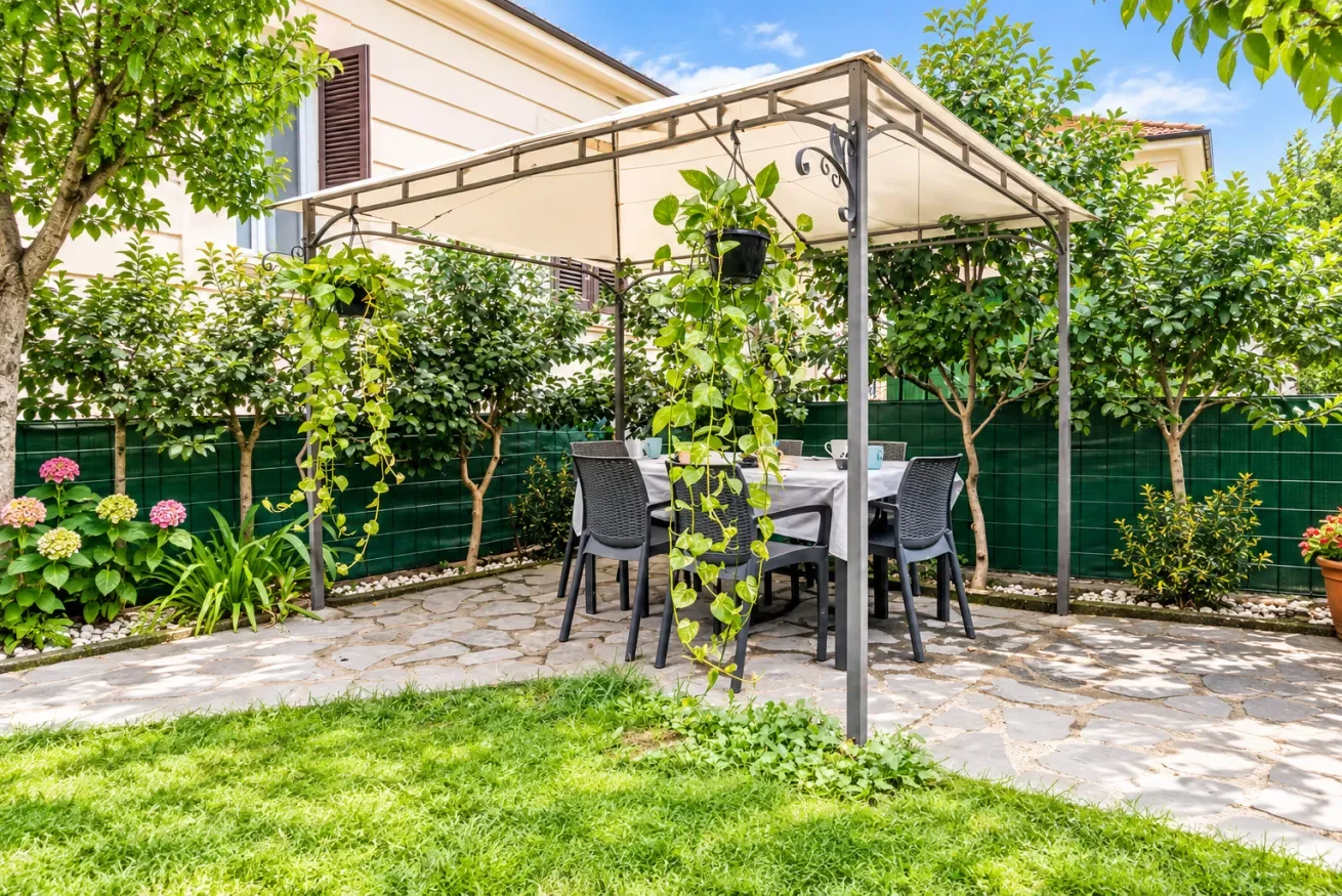 Un patio de jardín con una mesa de comedor bajo una pérgola cubierta.