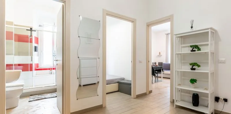 Un pasillo interior luminoso conecta con otras habitaciones y tiene una estantería blanca.