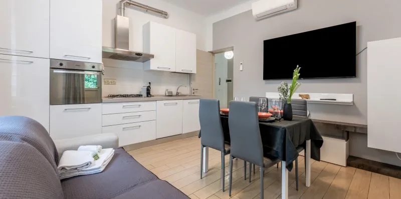 Una cocina moderna y comedor con gabinetes blancos y una mesa.