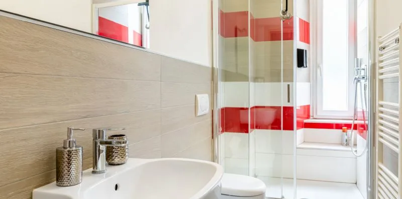 Un baño moderno con lavabo blanco, inodoro y ducha de vidrio.