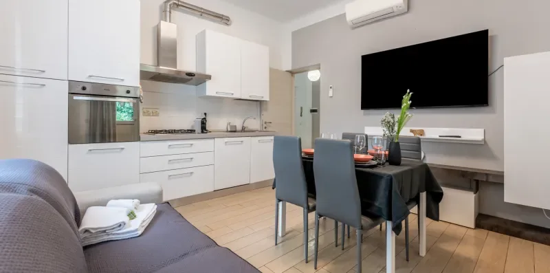 Una cocina moderna y zona de comedor con armarios blancos y una mesa.