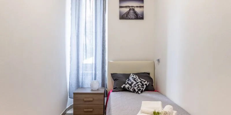 Un dormitorio con una cama individual, una mesita de noche y cortinas azules.