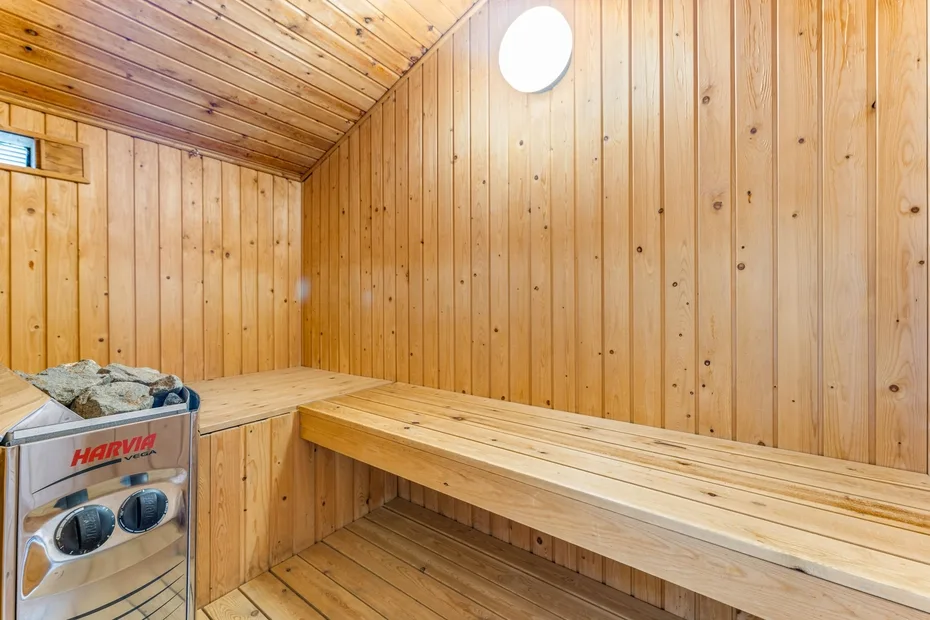 Una sauna revestida de madera con bancos escalonados y una estufa.