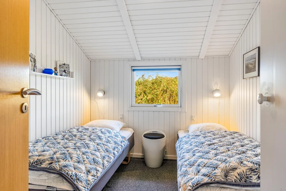 Un dormitorio con dos camas y una ventana que da a la vegetación.