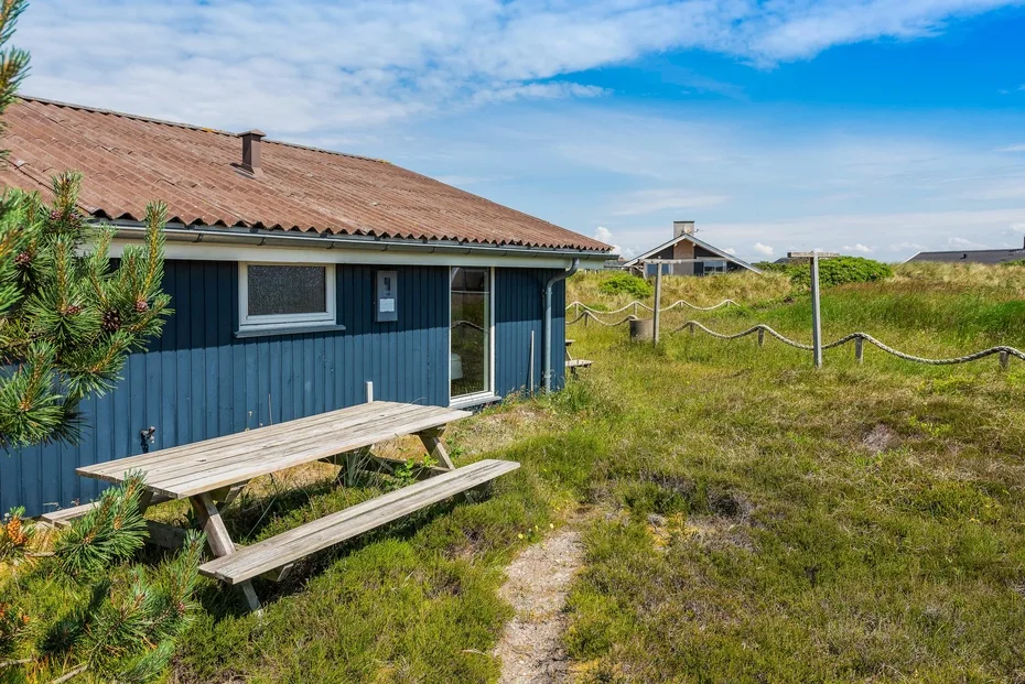 Una cabaña azul junto a una zona de hierba con una mesa de picnic.