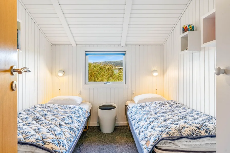 Un dormitorio compacto con dos camas individuales y una ventana pequeña.