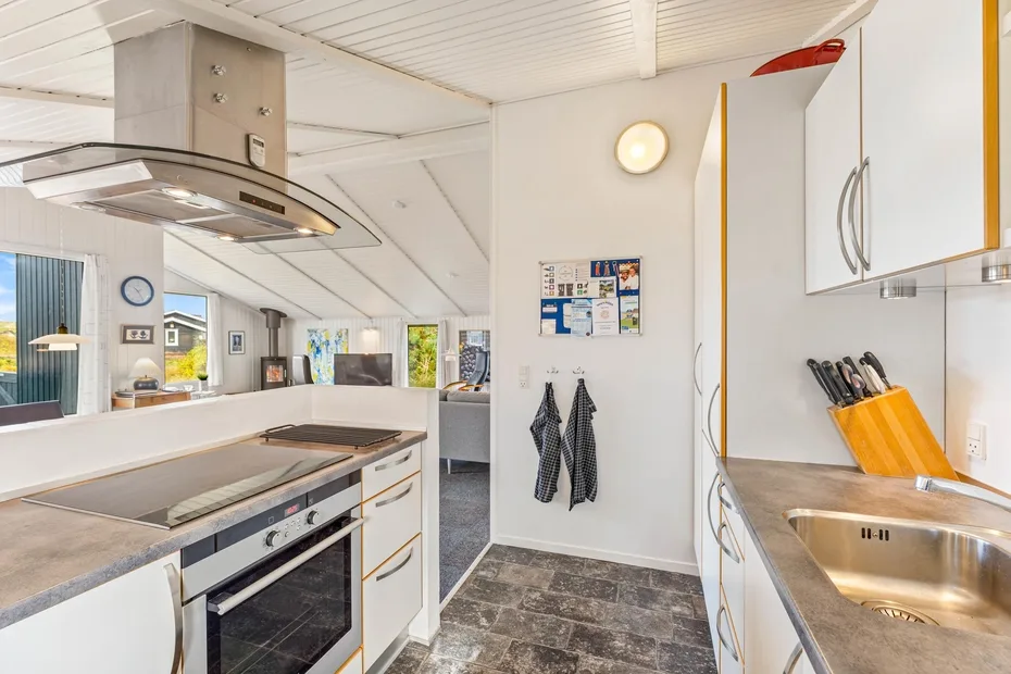 Una cocina luminosa con una encimera central para cocinar, horno y fregadero de acero inoxidable.