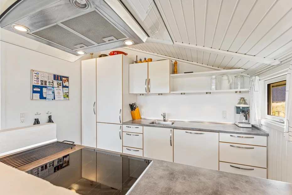 Una cocina luminosa con gabinetes blancos, una encimera y un fregadero.
