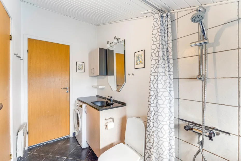 Un baño con lavabo, inodoro y ducha detrás de una cortina estampada.
