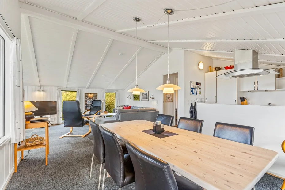 Un espacio abierto de comedor y sala de estar con una mesa larga de madera y asientos.
