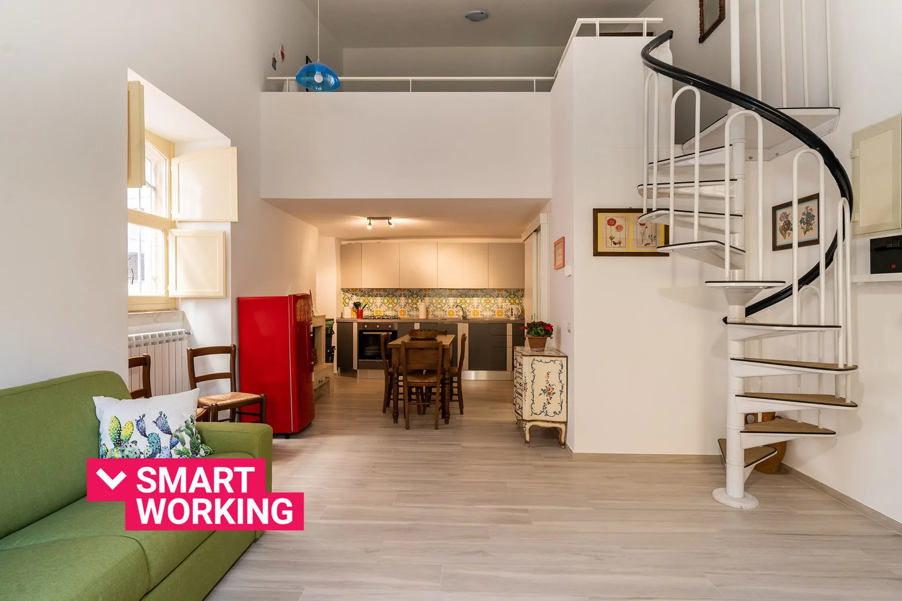 A bright open-plan living and dining area with a kitchen in the background.