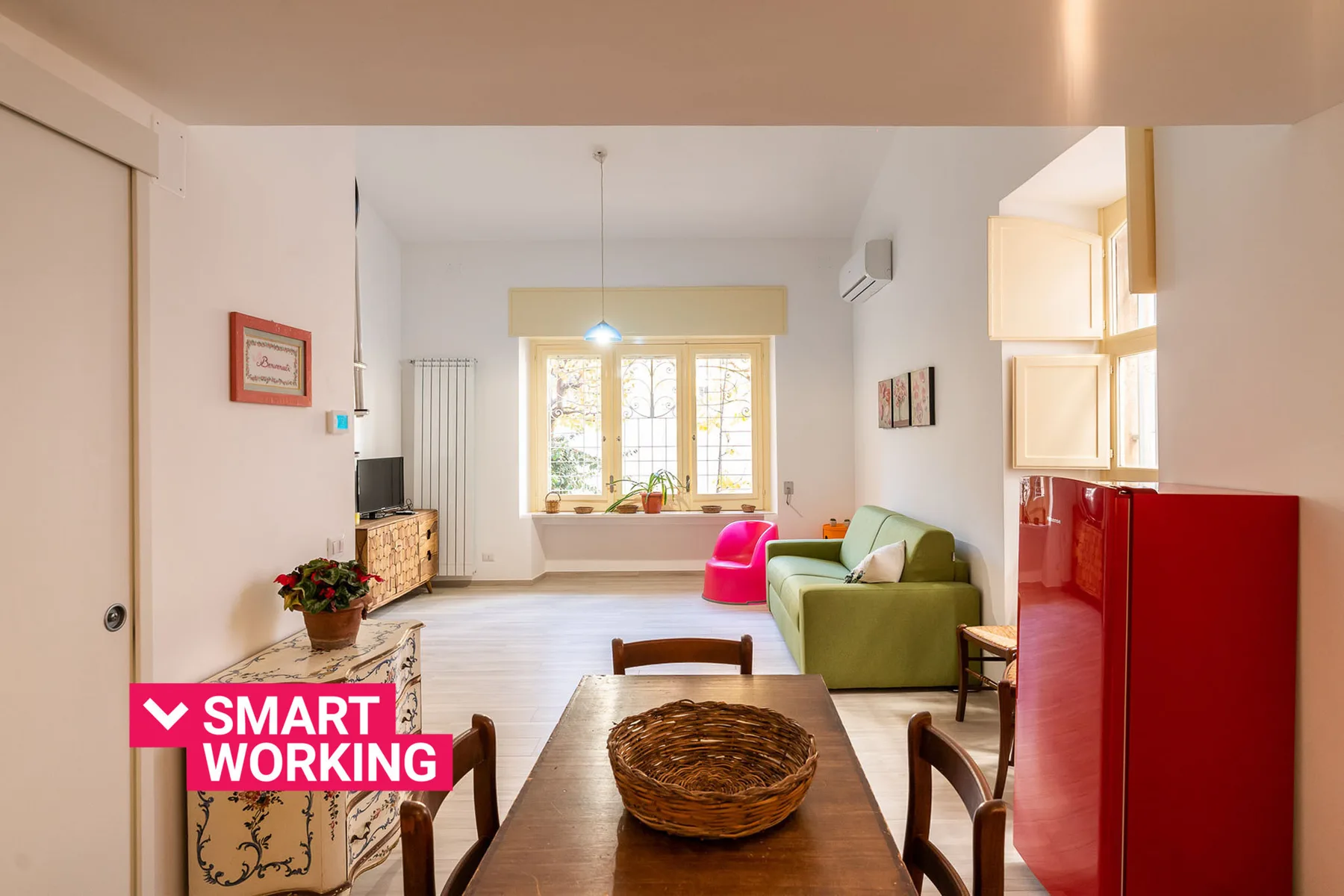 A bright living room has a dining table, green seating, and a large window.