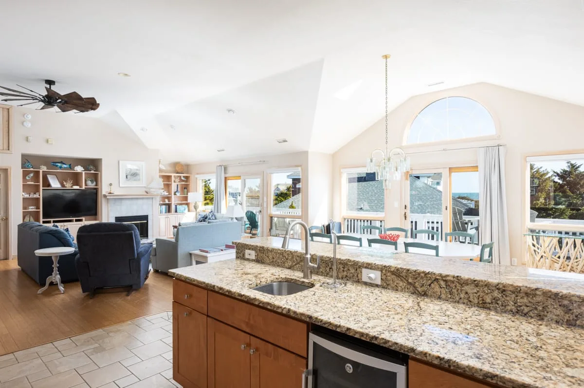 An open kitchen and living area with a stone-topped island and large windows.