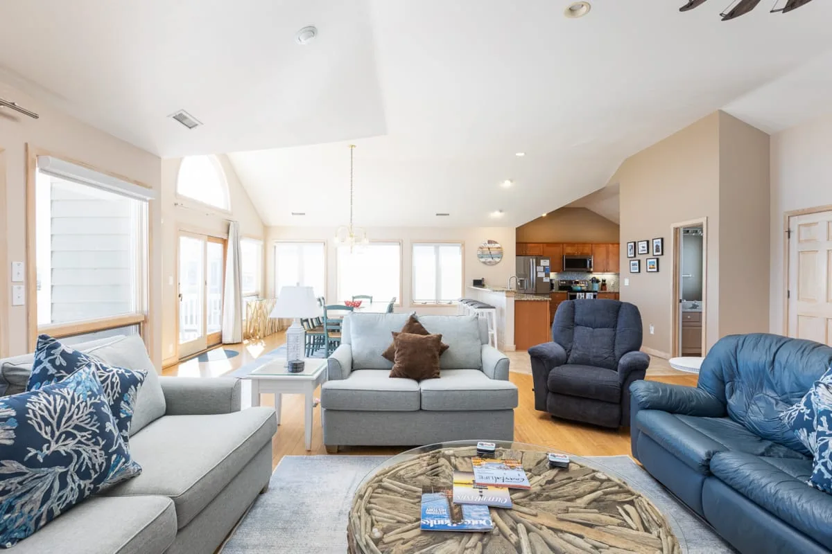 A bright living room with sofas and armchairs arranged around a coffee table.