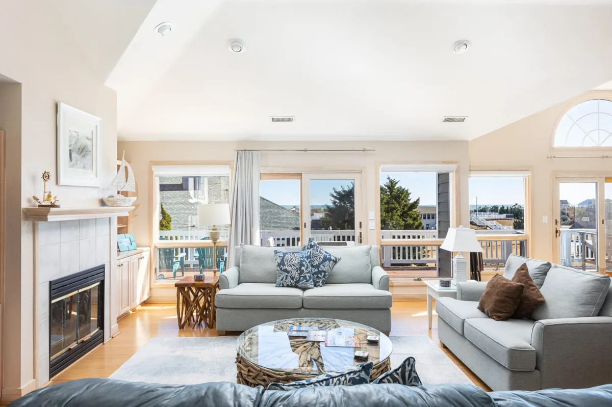 A bright living room with seating, a fireplace, and large windows.