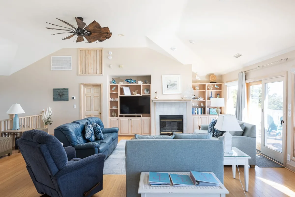 A bright living room with seating, a fireplace, and large windows.