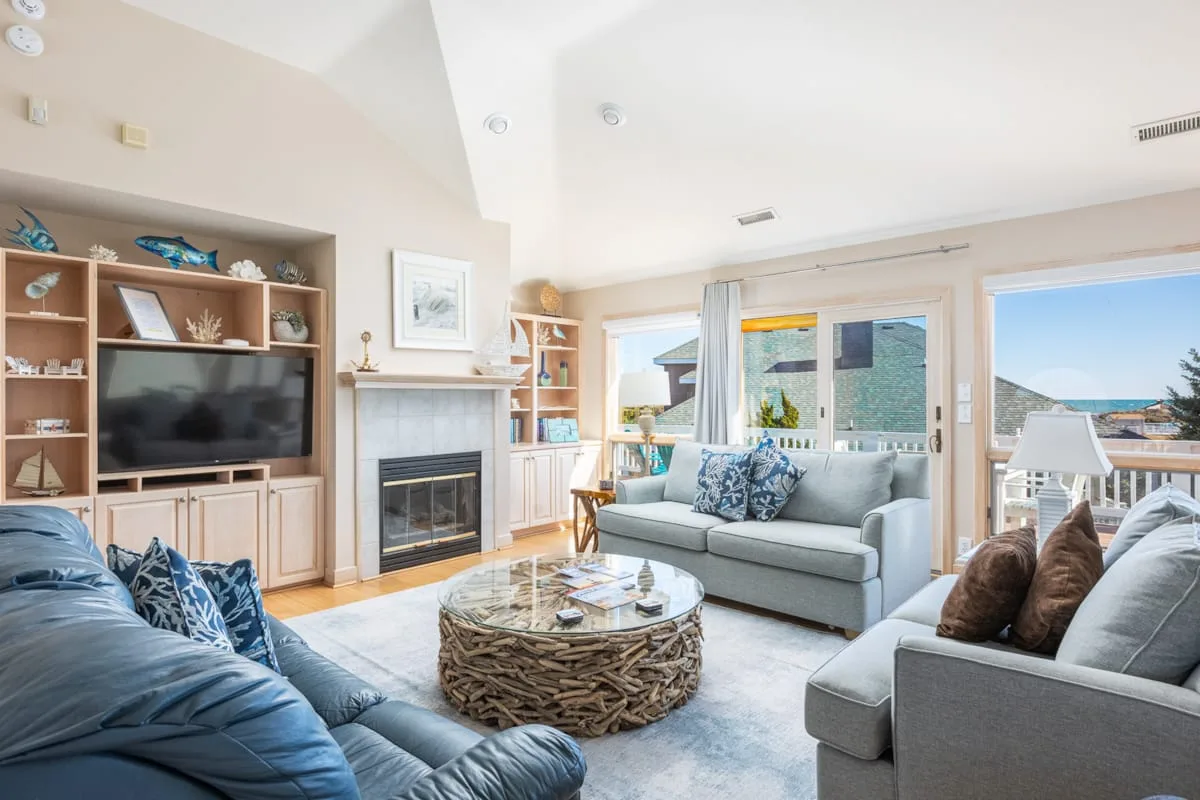 A bright living room with seating, a coffee table, and a fireplace.
