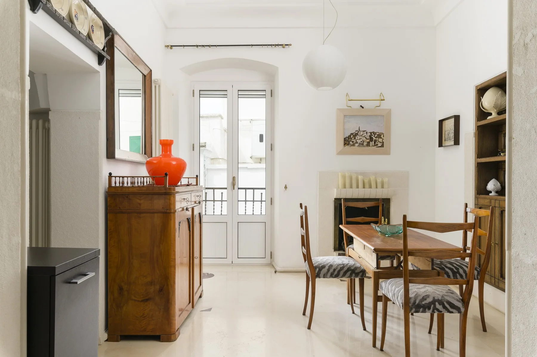 Un comedor luminoso con una mesa y sillas de madera junto a unas puertas de vidrio altas.