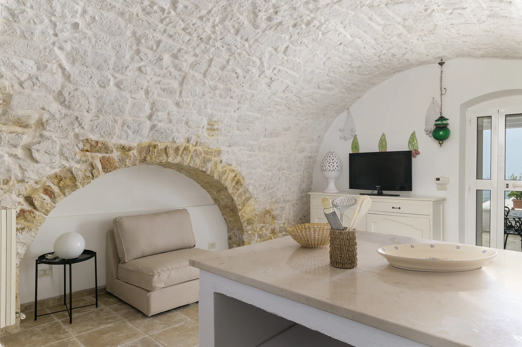Una habitación luminosa con un nicho de piedra en arco, asientos y una mesa grande en el centro.