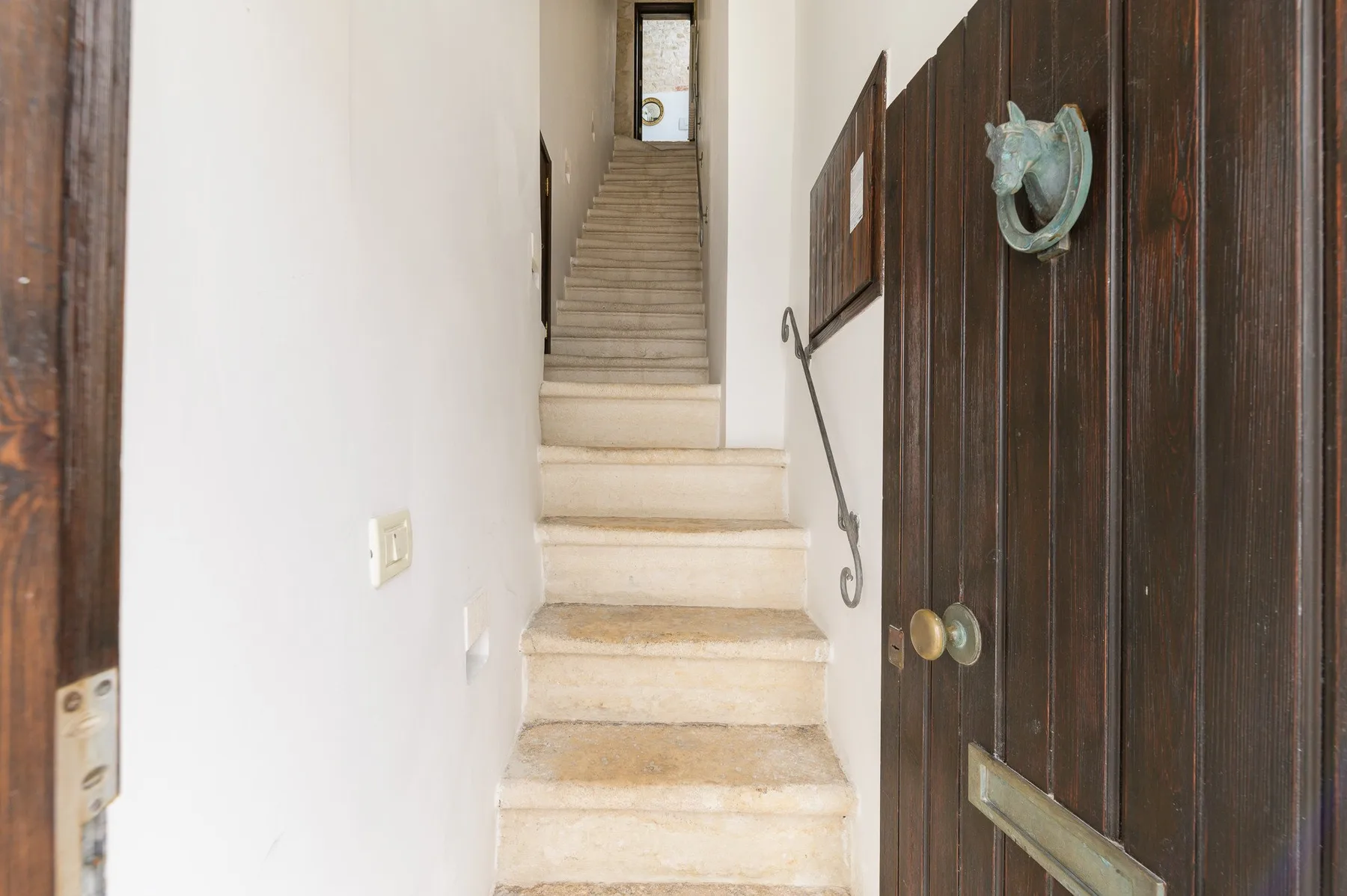 A stairwell rises beside an open dark wooden door.