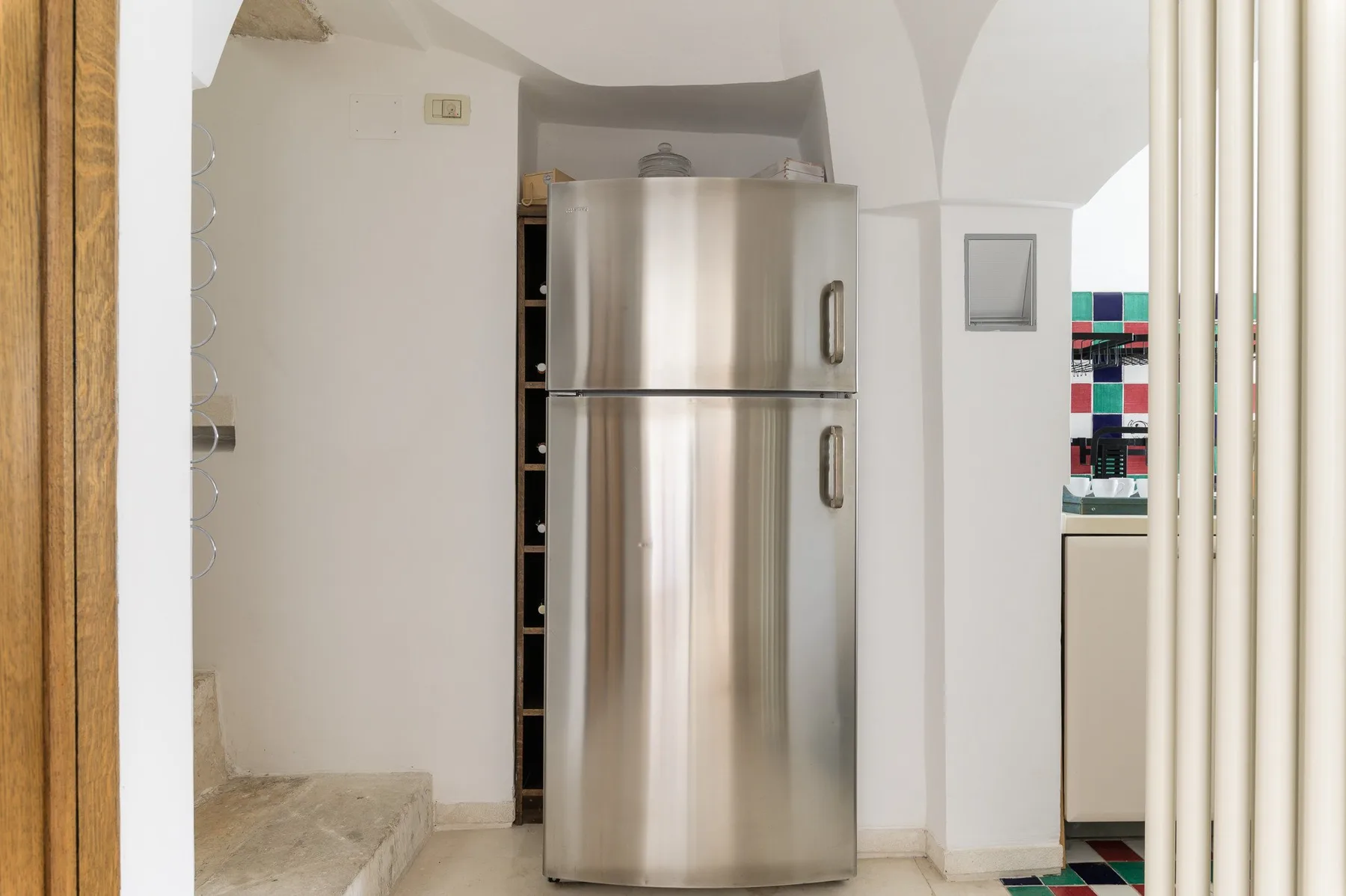 Una cocina con un refrigerador de acero inoxidable bajo un arco curvo.