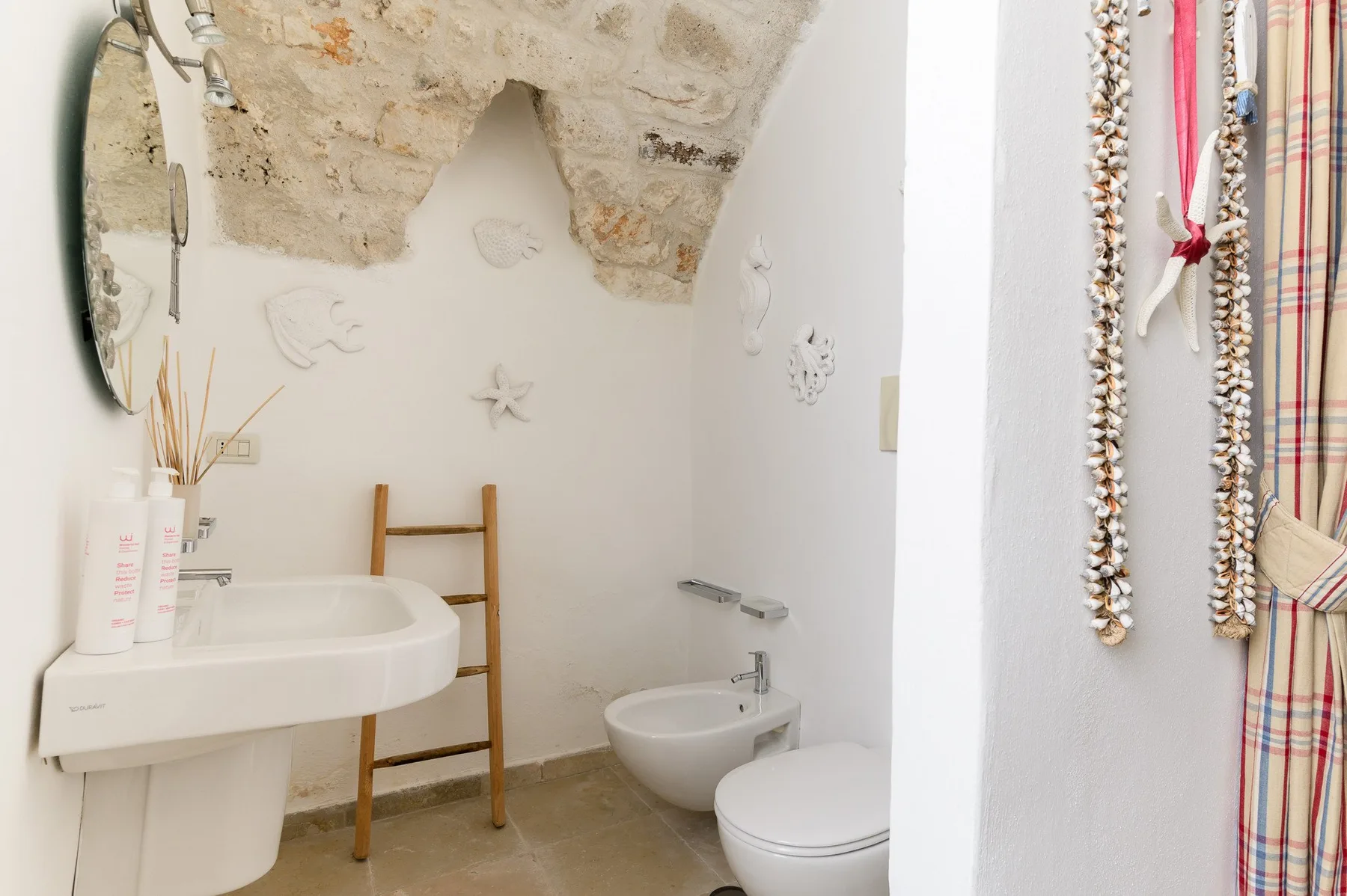Un baño pequeño con lavabo, inodoro, bidé y techo de piedra expuesta.