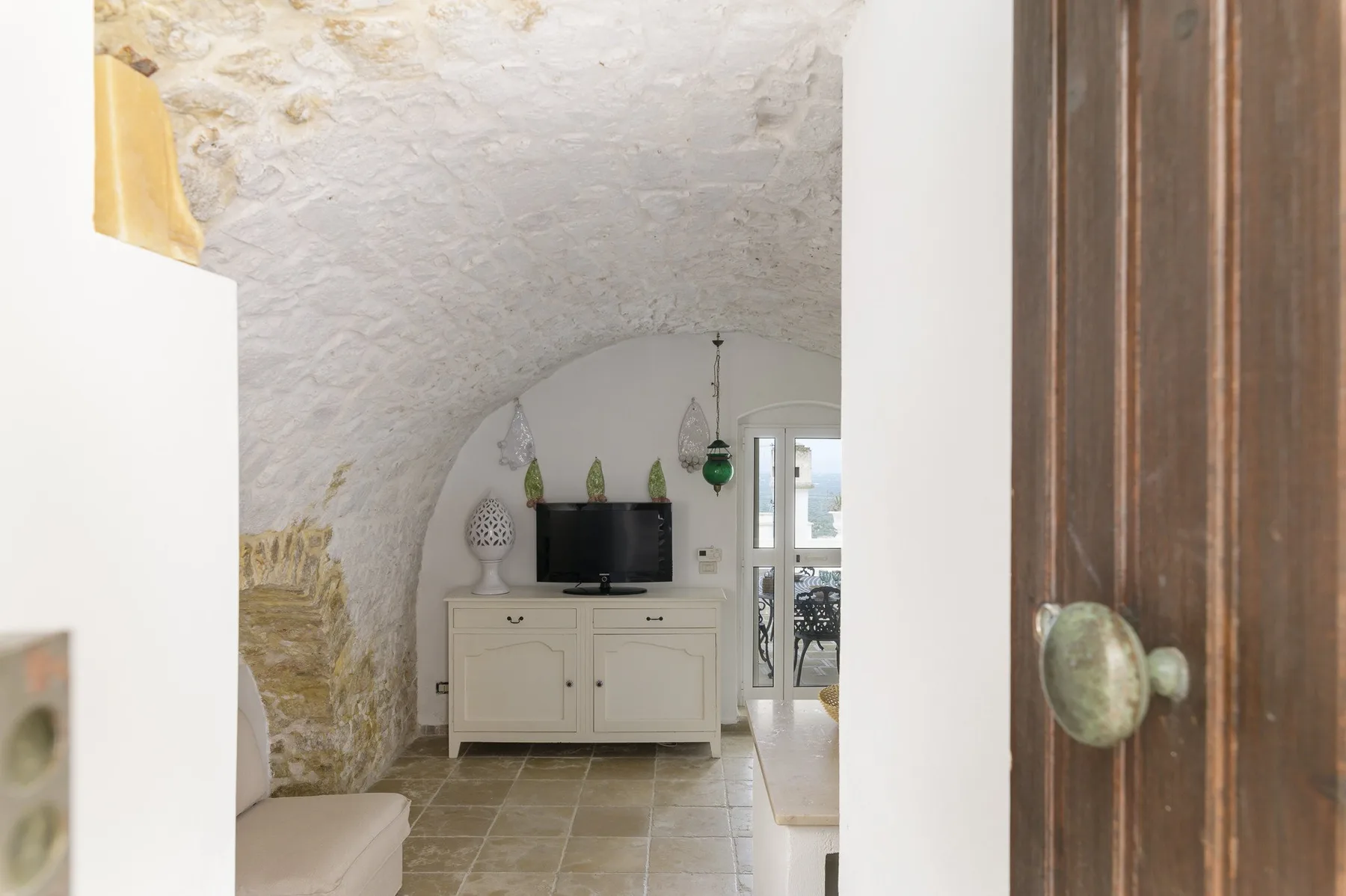 Una sala abovedada con un televisor sobre un mueble blanco.