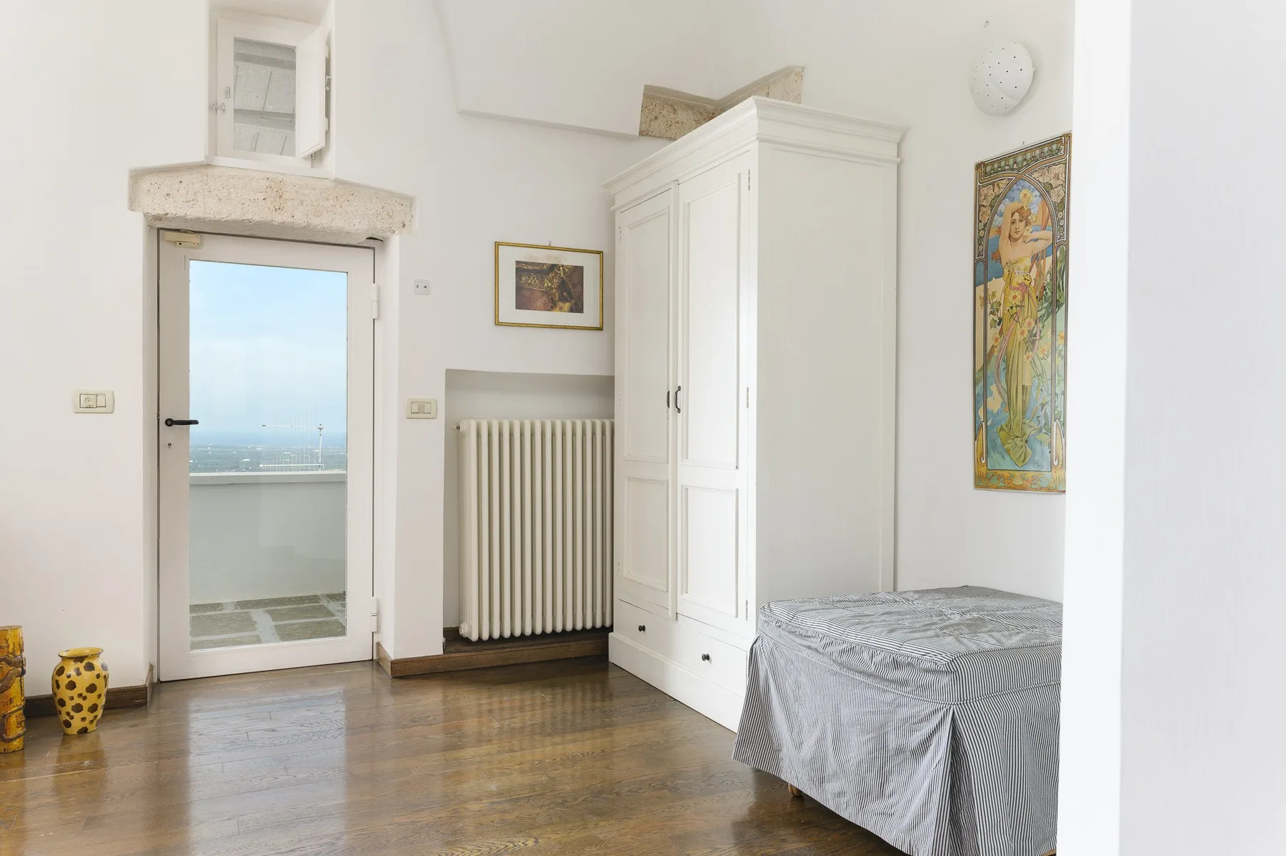Un dormitorio luminoso con una cama individual, un armario blanco y un radiador.