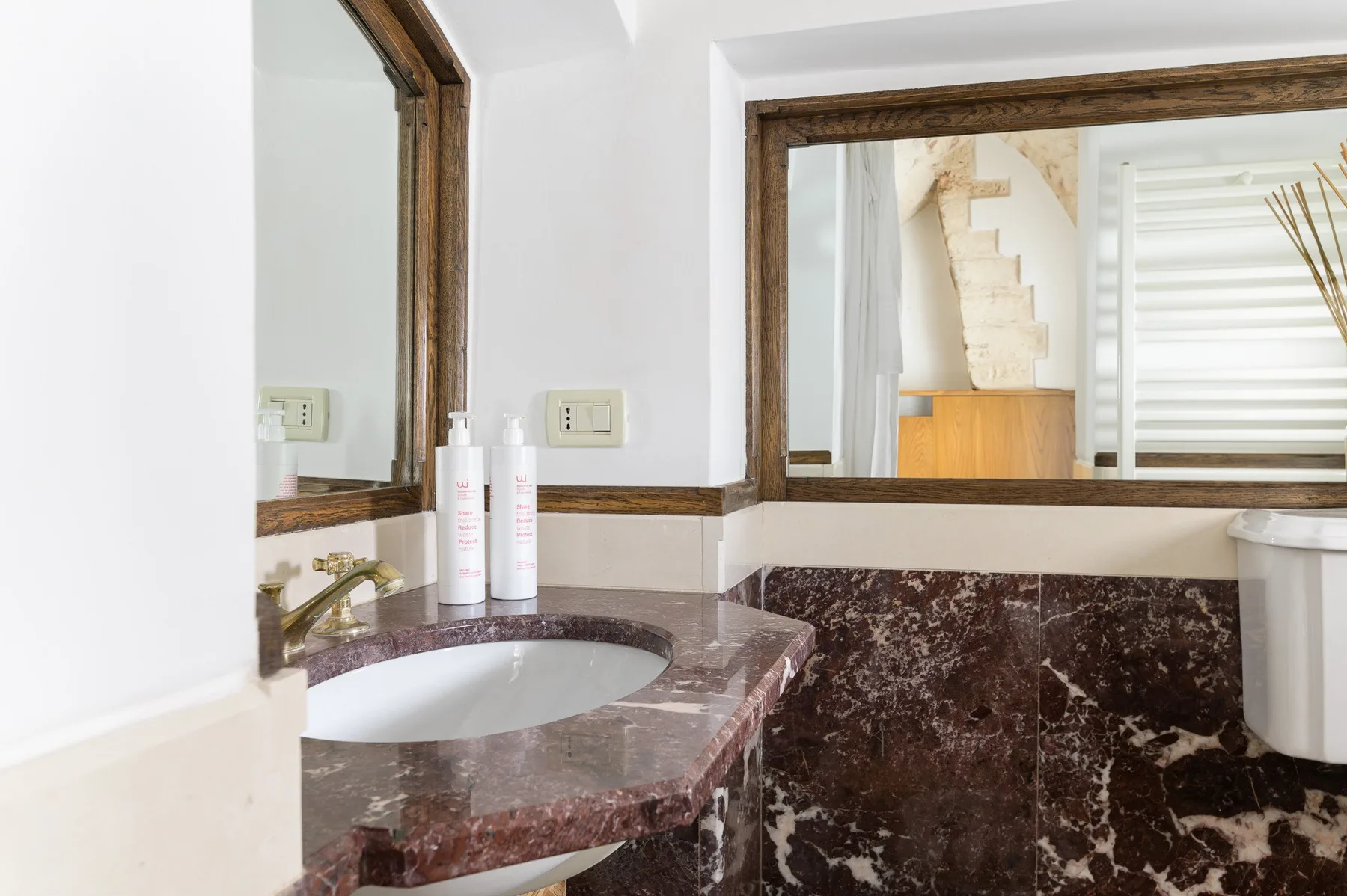 Un lavabo de baño con una cuenca está debajo de un gran espejo enmarcado.