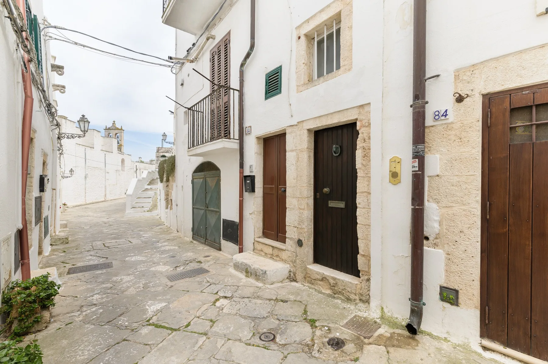 Una calle estrecha empedrada pasa entre edificios blancos muy próximos.