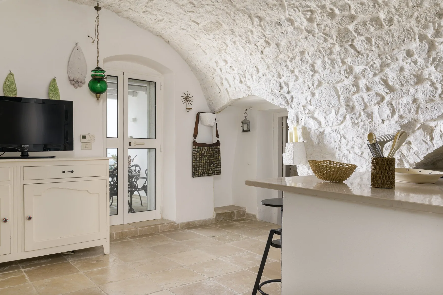 Una cocina luminosa con una barra blanca bajo un techo de piedra.