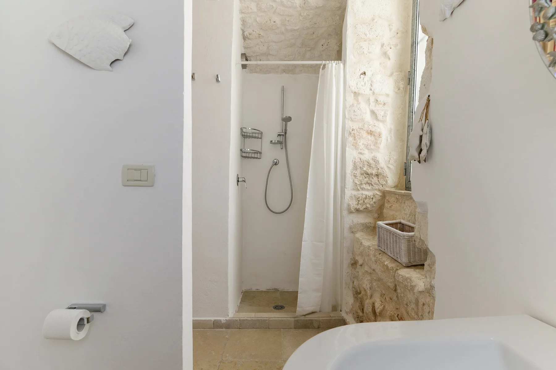 Zona de ducha en un baño con cortina y un saliente de piedra.