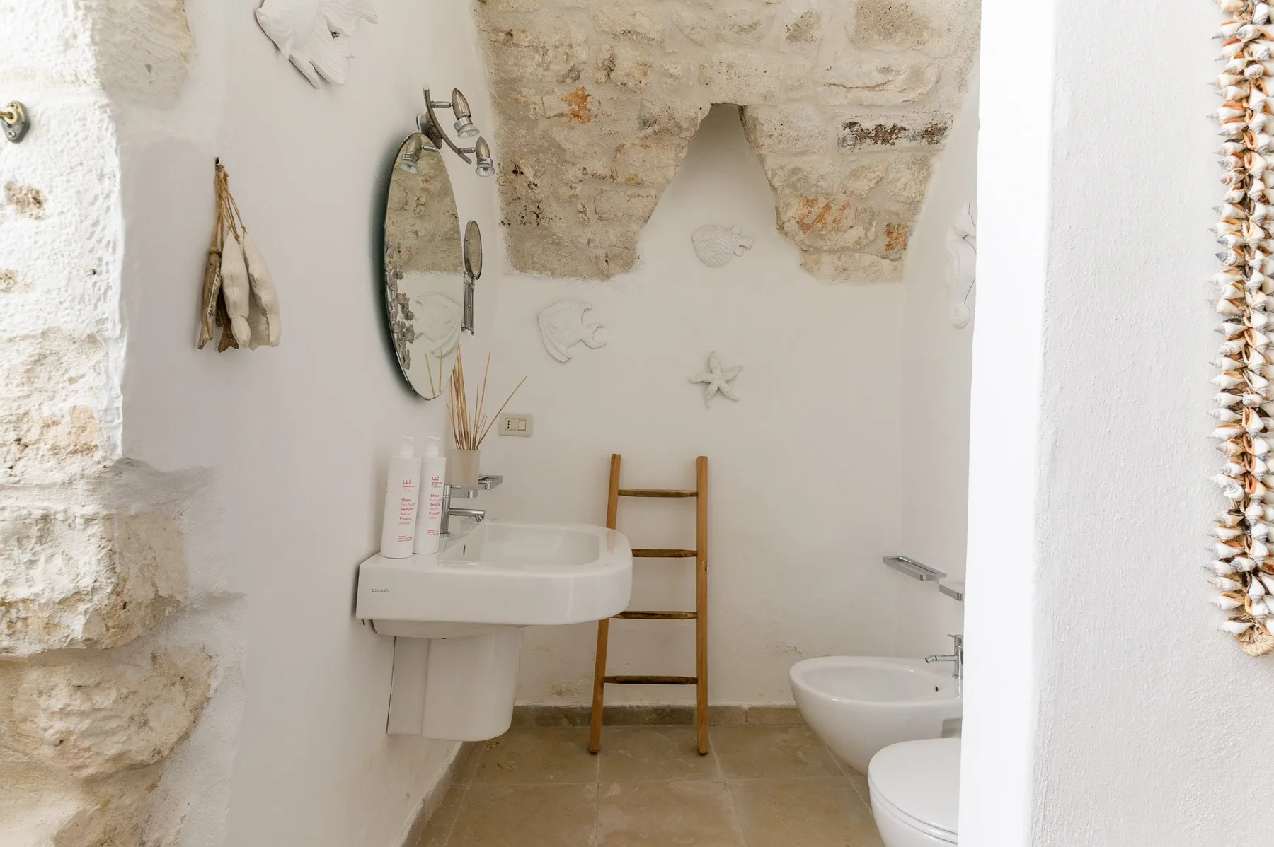 Un baño rústico con lavabo, espejo y toallero de escalera.