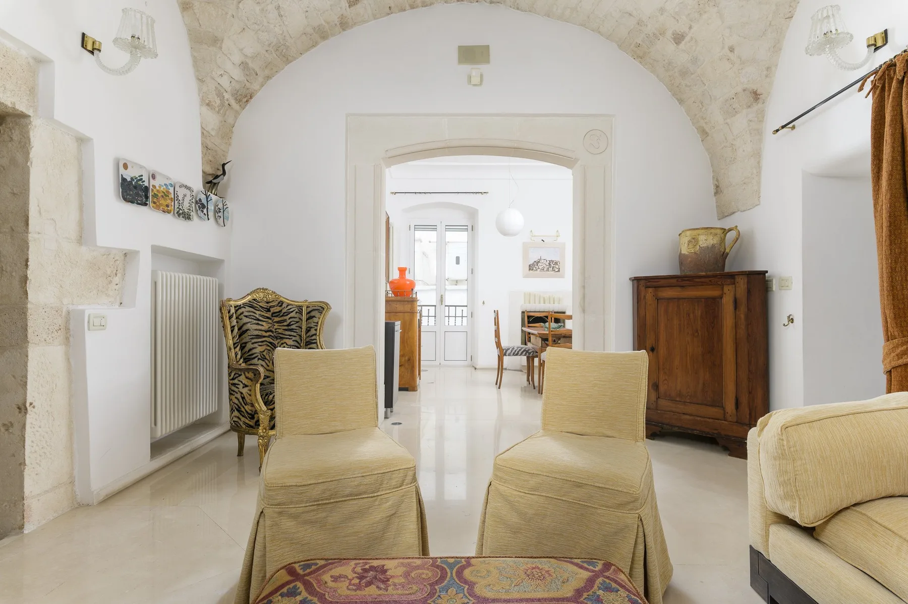 Una sala de estar luminosa con dos sillones bajo un amplio arco de piedra.