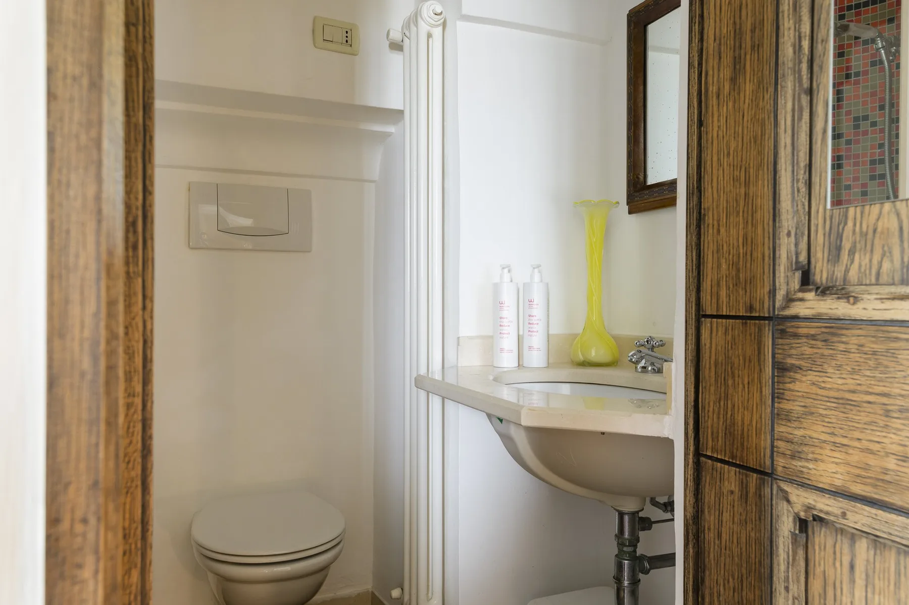 Un baño con un inodoro y un lavabo debajo de un espejo.