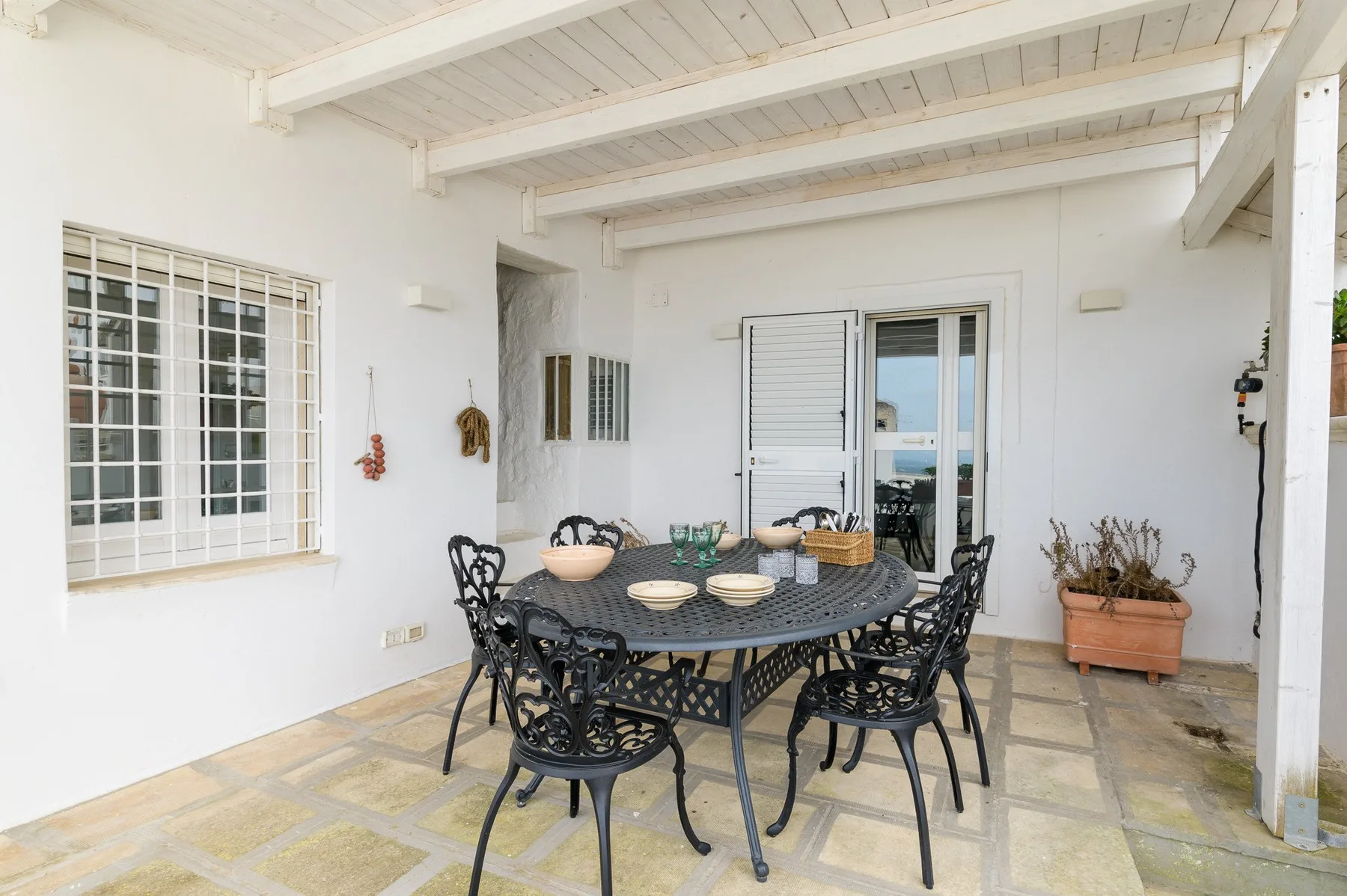 Un patio cubierto con una mesa redonda de exterior y sillas.
