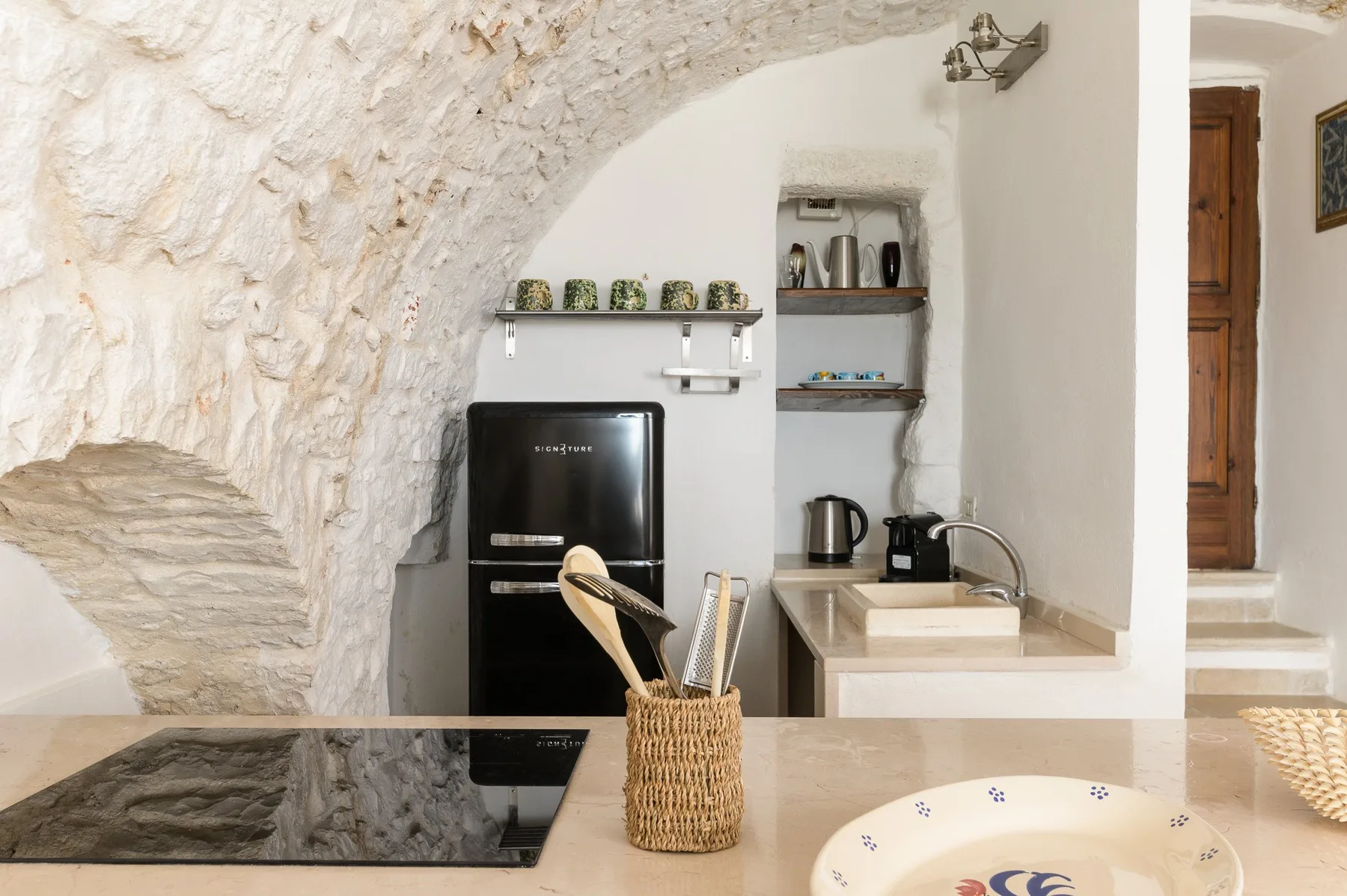 Una cocina compacta bajo un arco de piedra, con una encimera y electrodomésticos.